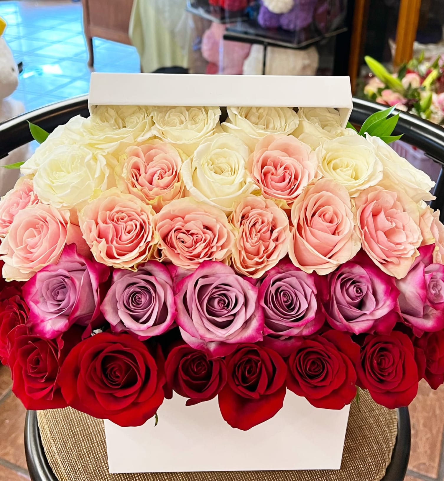 Boxed arrangement of roses in white, pink, lavender, and red