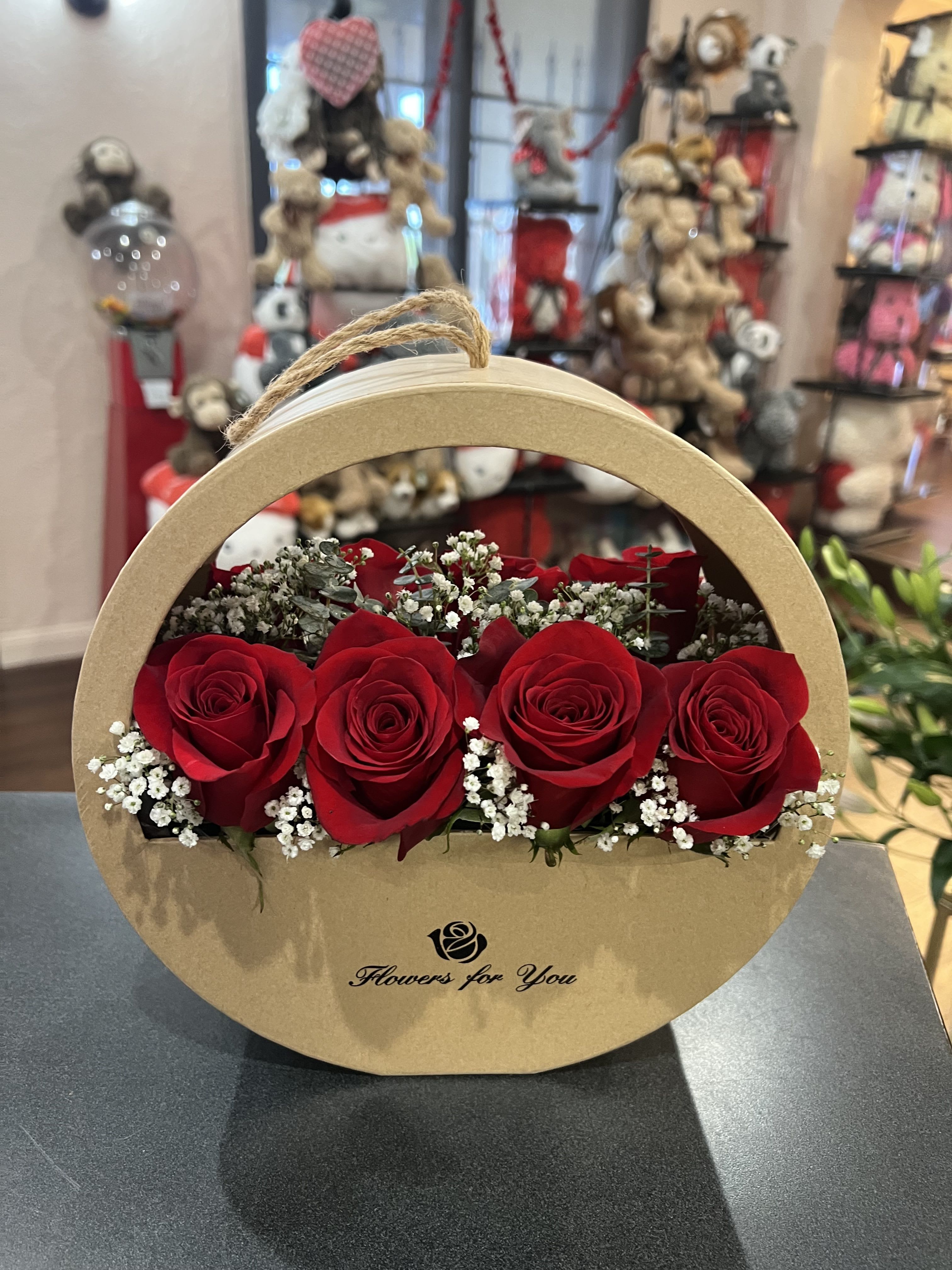 Red roses arranged in a round cardboard gift box with baby's breath