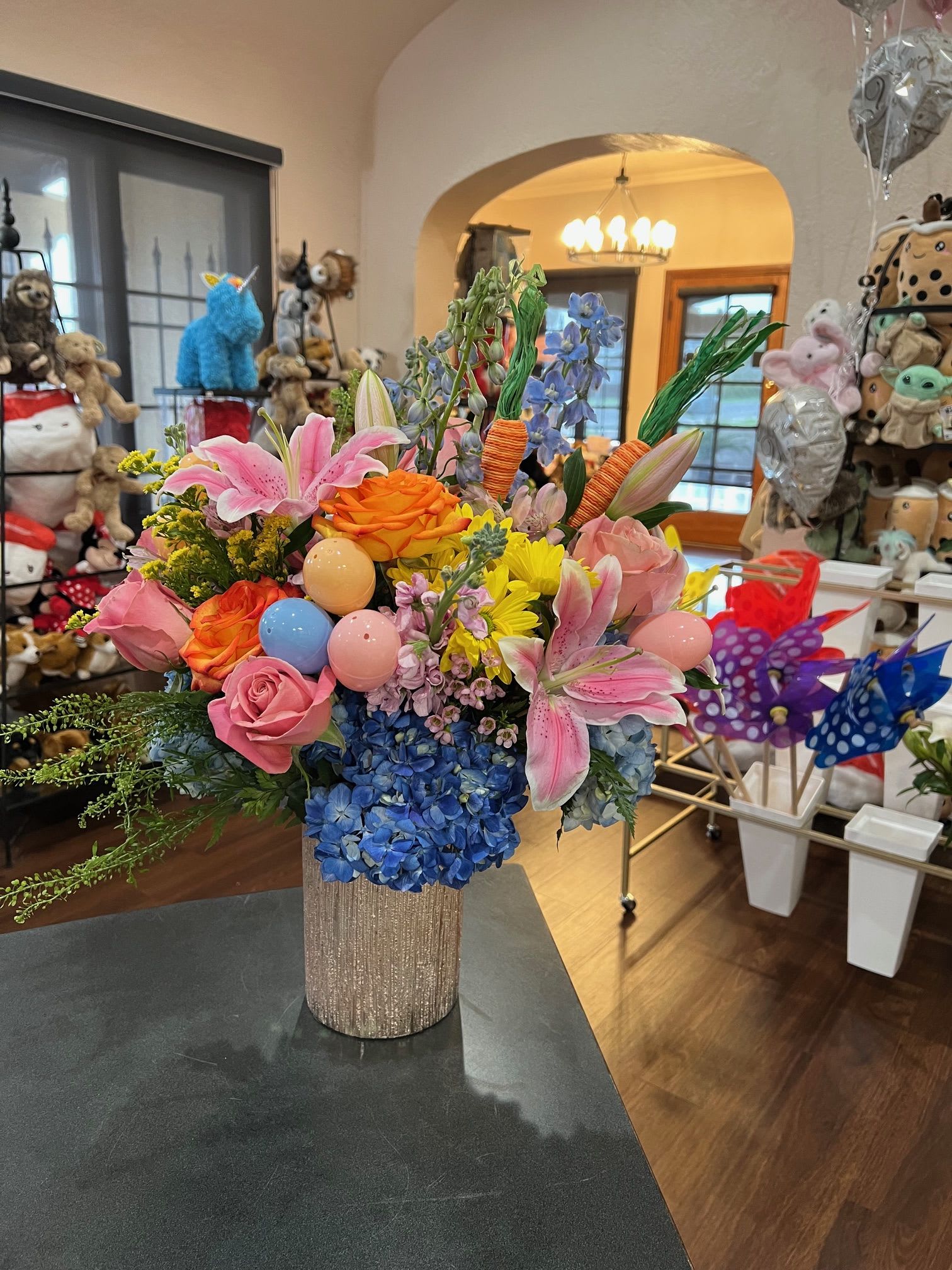 Colorful bouquet with lilies, roses, hydrangeas, and decorative eggs in a glittery vase