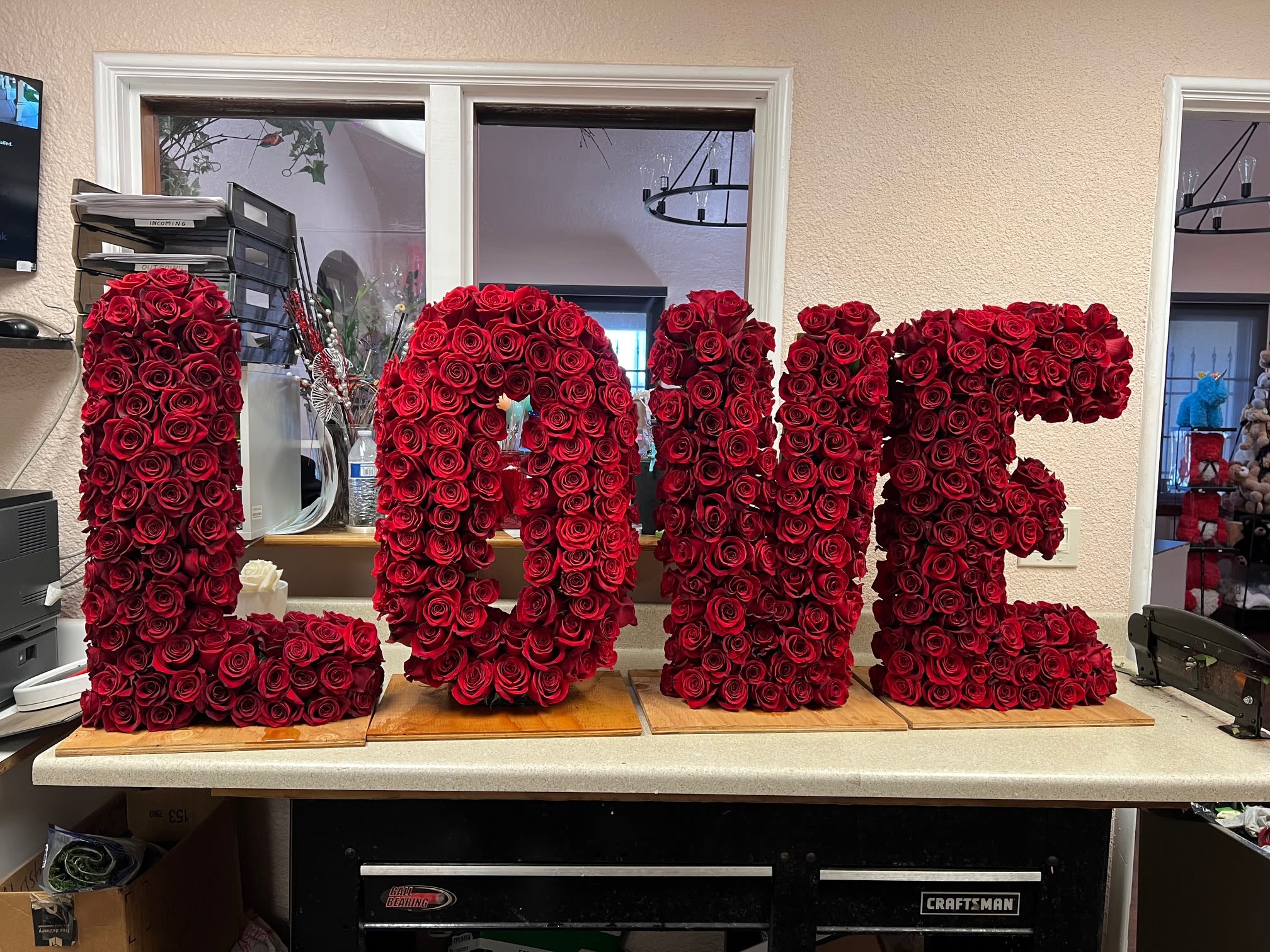 Large red rose letters spelling "LOVE" on wooden bases