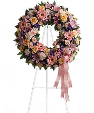 Floral wreath on a white stand with pink ribbon