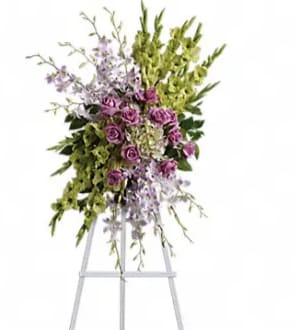 Standing floral spray with purple roses and green orchids on an easel