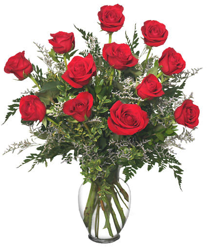 Red roses arranged in a clear glass vase with greenery