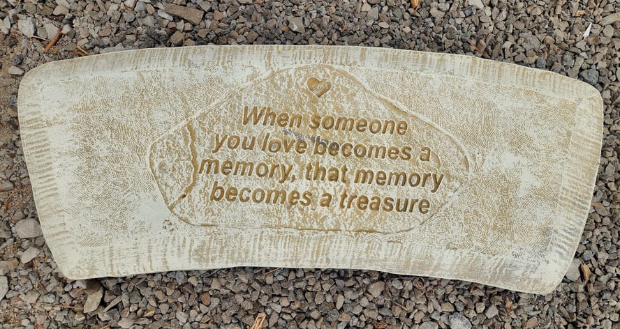 Memorial stone with an engraved quote on a gravel surface