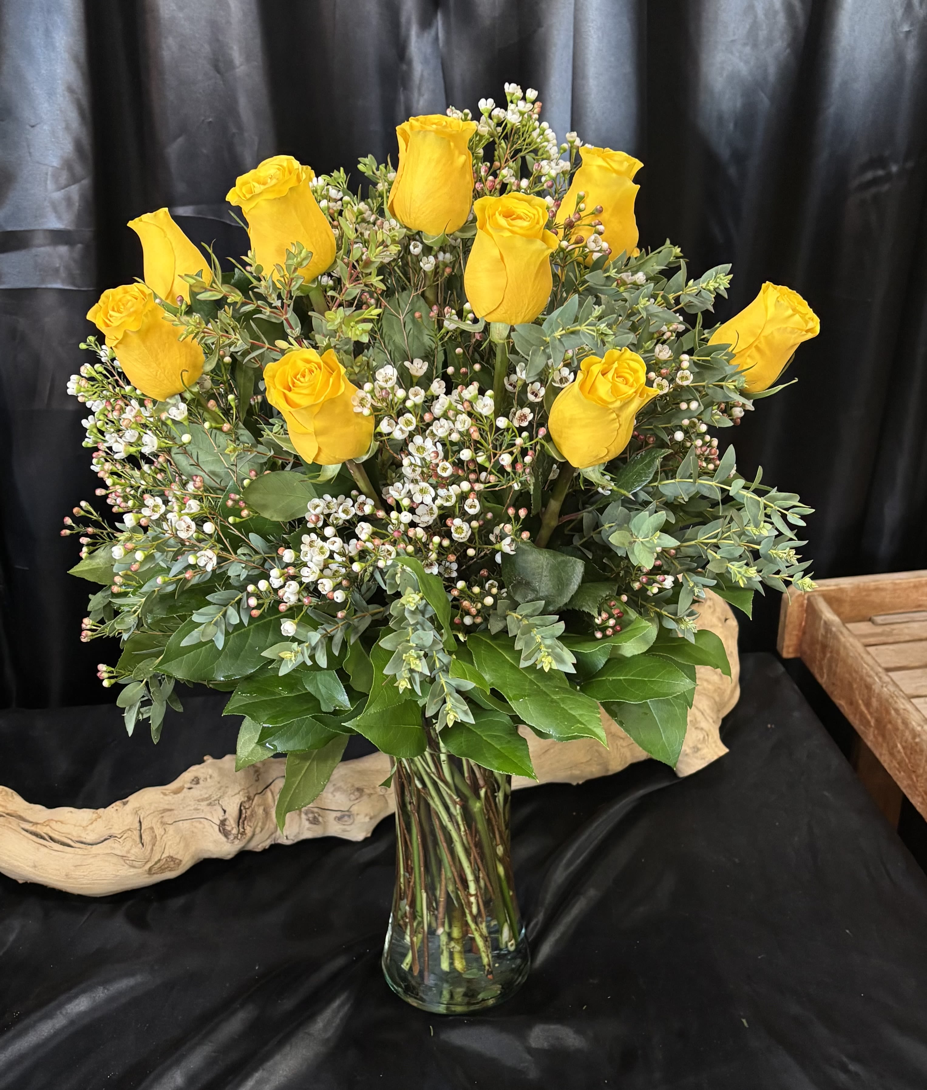 Yellow roses arranged in a clear glass vase with small white filler flowers