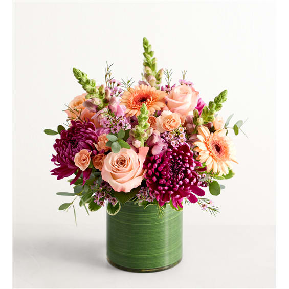 Pink and peach flowers arranged in a green cylindrical vase