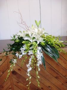 White lily arrangement with cascading orchids and green accents