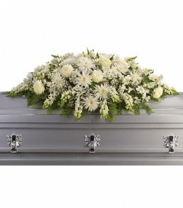 White floral casket spray on a gray casket