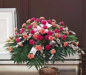Pink and peach carnation casket spray with white ribbon