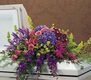 Colorful floral casket spray with purple, pink, and blue blooms