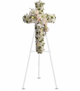 Floral cross arrangement on a white easel with pale blooms