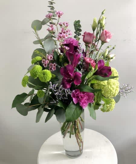 Tall bouquet of purple and pink flowers in a clear glass vase