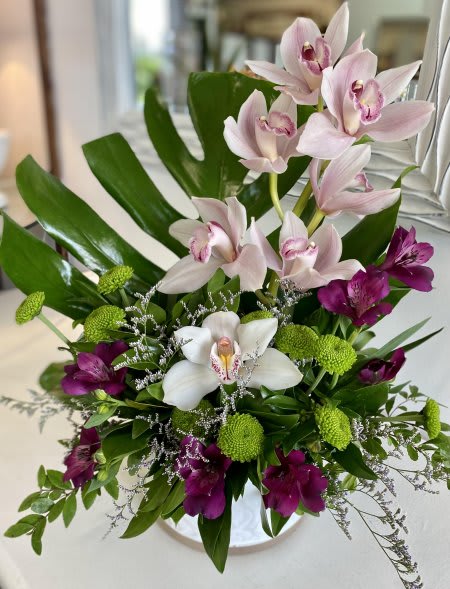 Arrangement of pink and white orchids with green button mums in a vase