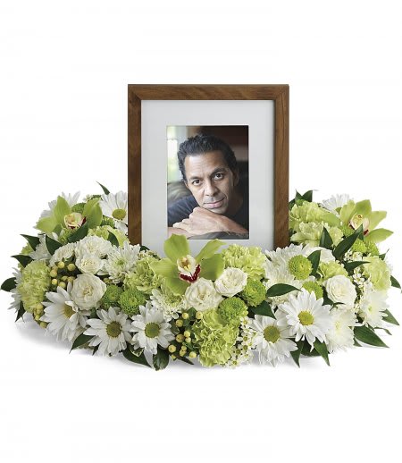 Ring of white daisies and green flowers encircling a wooden photo frame for a memorial display