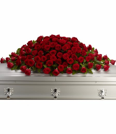 Spray of red roses arranged across a silver casket