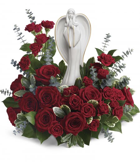 Red rose arrangement surrounding a white angel figurine