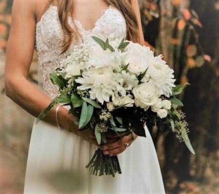 Bride holding a white bouquet with roses and daisies