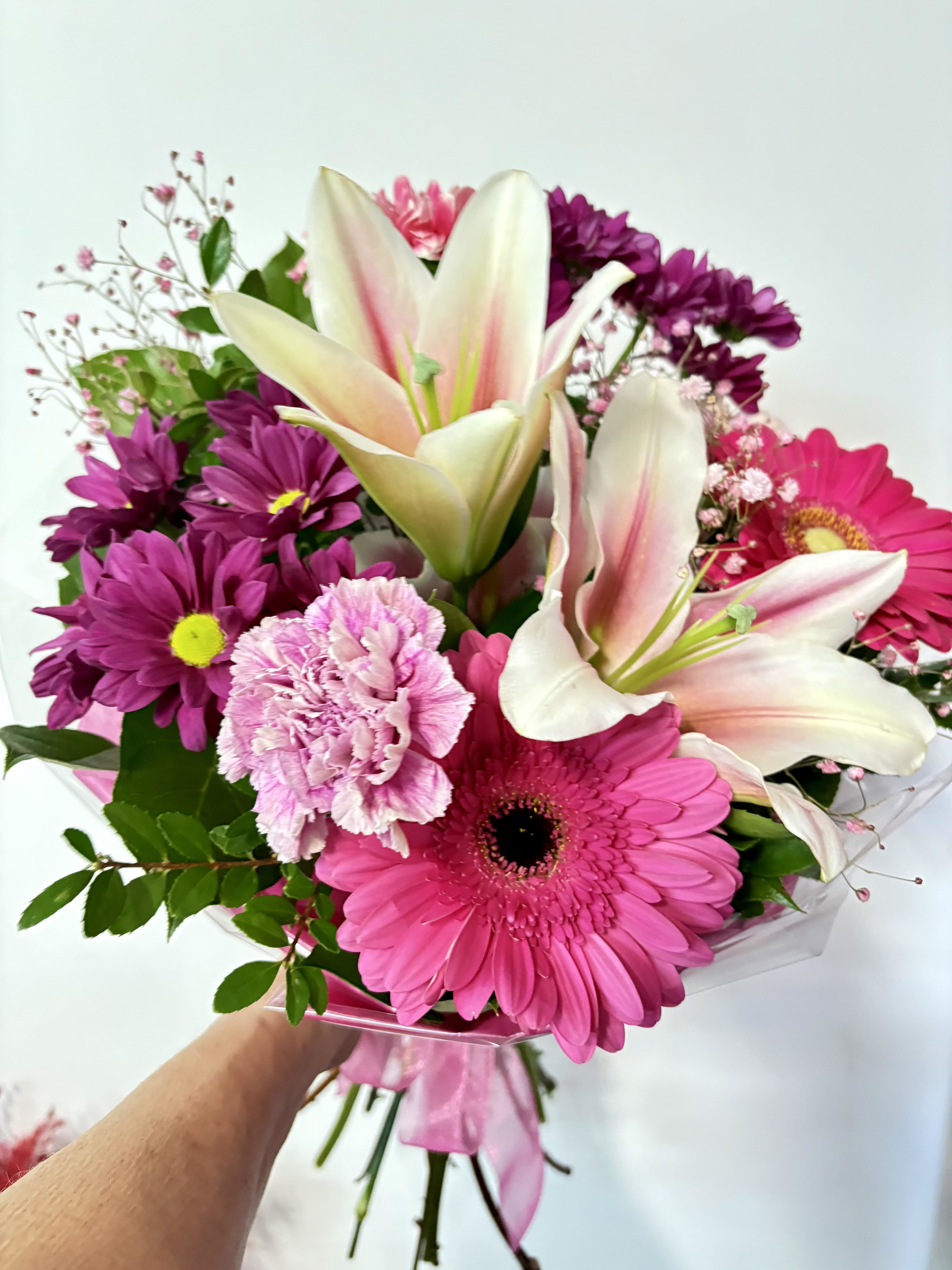 Hand Tied Bouquet #18 - Hand-tied bouquet with pink gerbera, white-pink lilies, purple mums, ruffled carnation; clear wrap &amp; pink ribbon