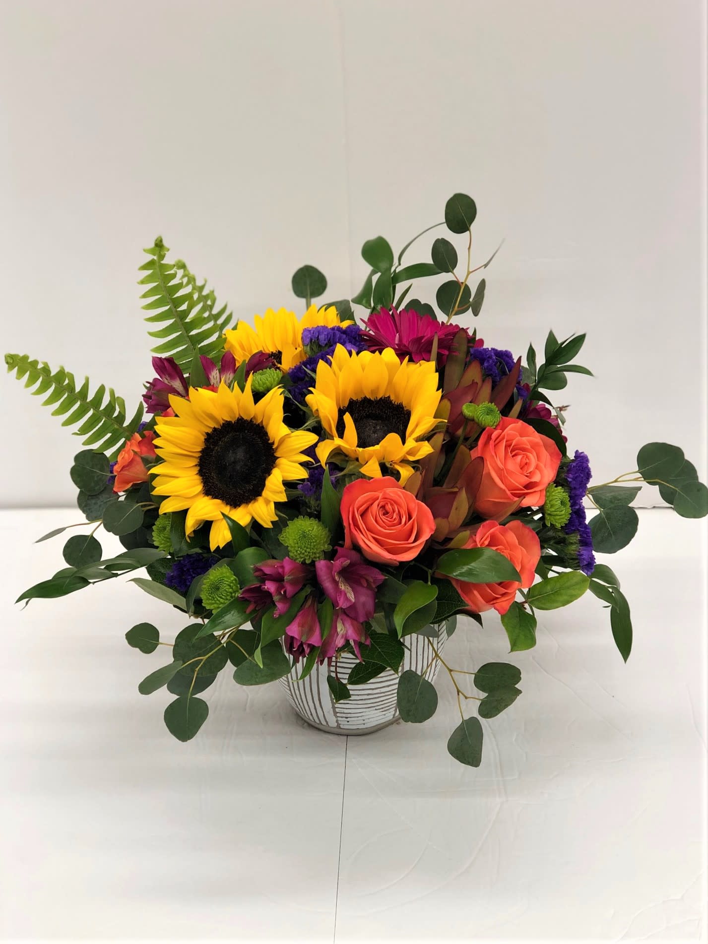 Bouquet of sunflowers and coral roses in a striped vase