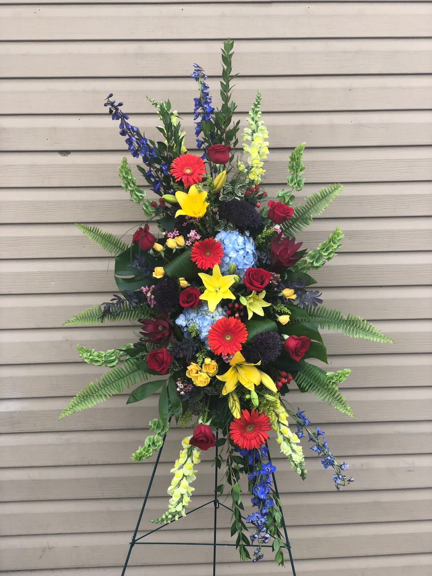 Tall standing floral spray with red, yellow, blue, and purple blooms