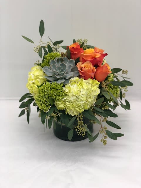 Orange roses and green hydrangeas in a black container