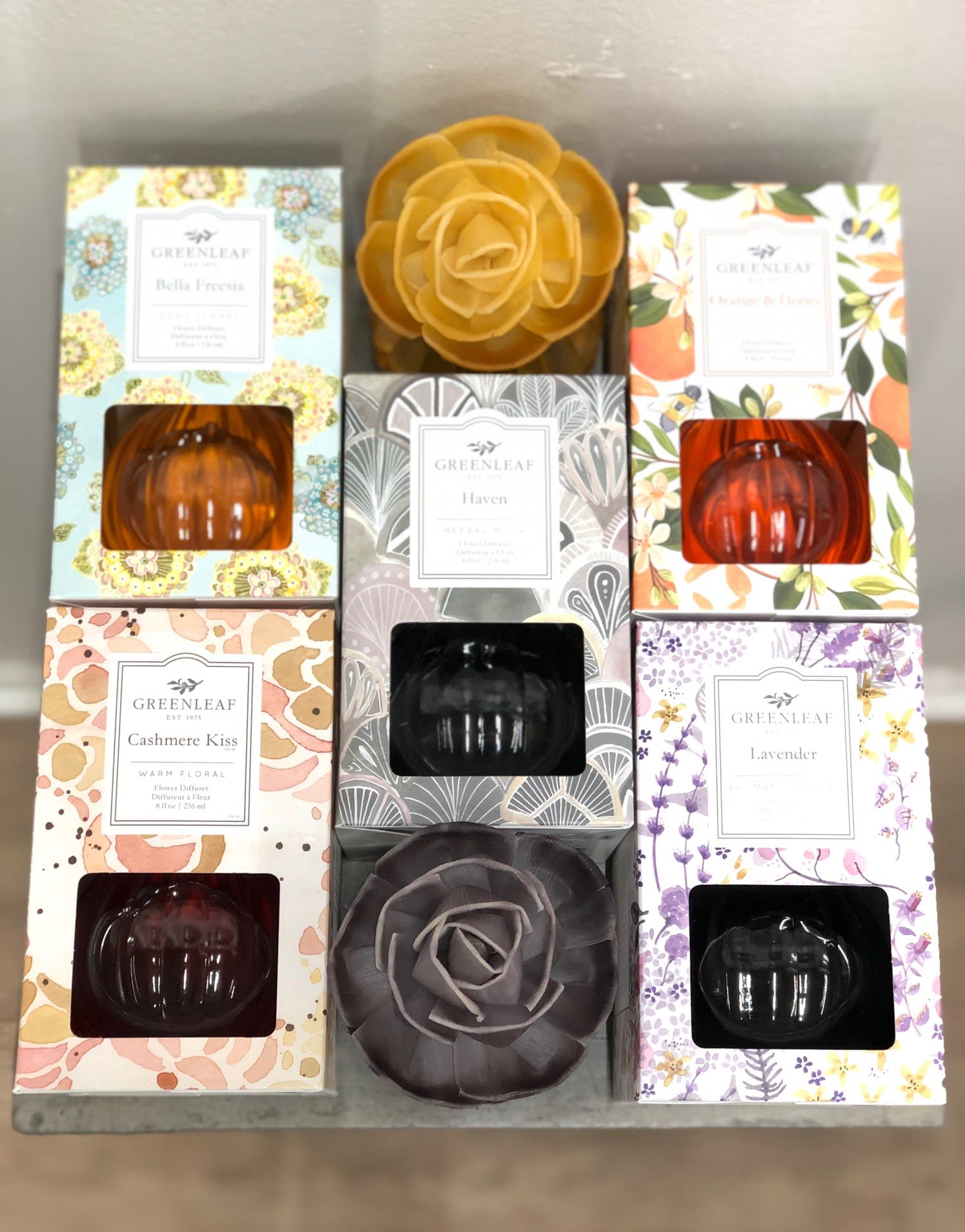Assorted boxed home fragrance diffusers with floral designs and pumpkin-shaped glass bottles on a shelf