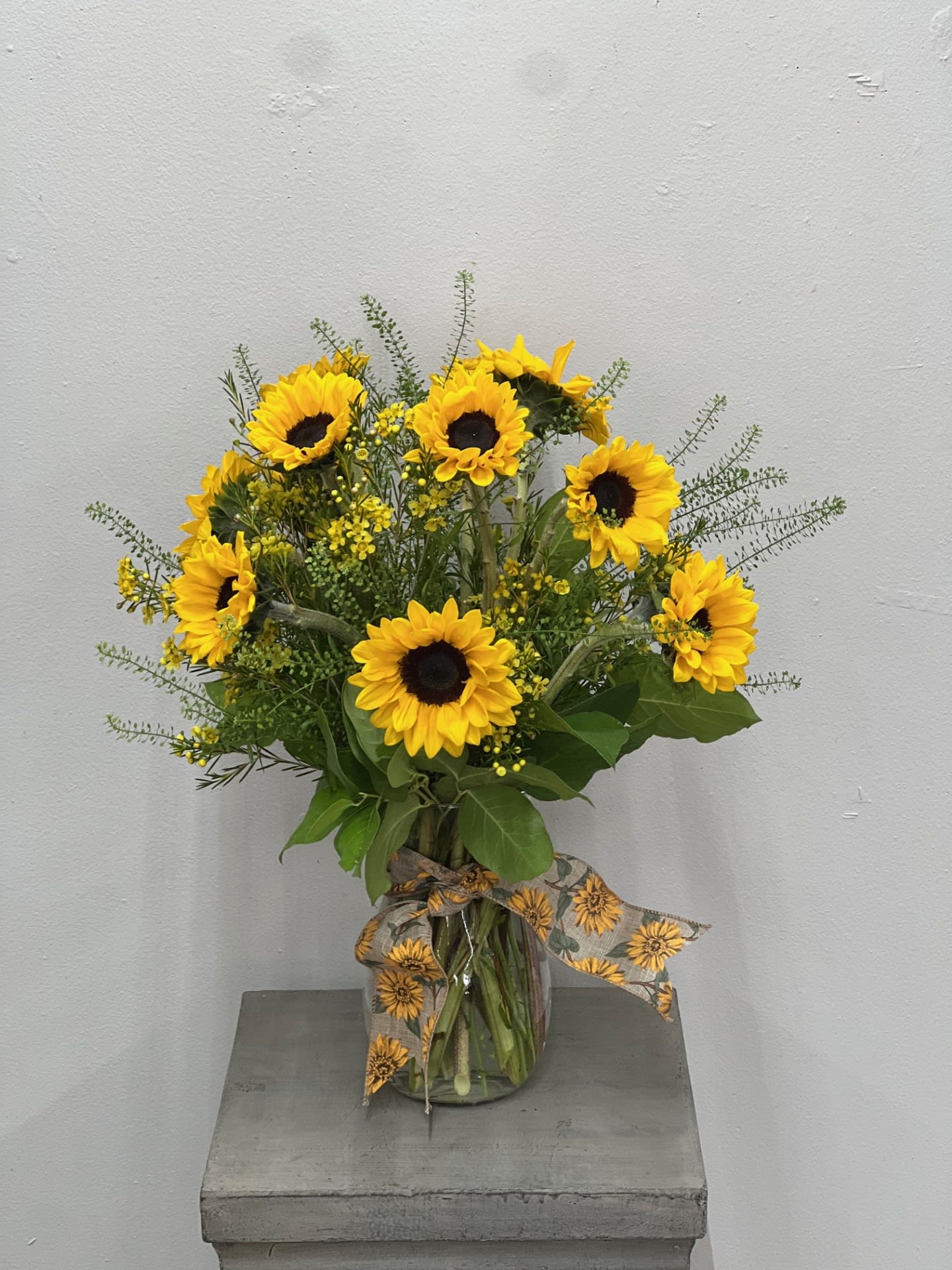Sunflower bouquet in a clear glass vase with a patterned ribbon