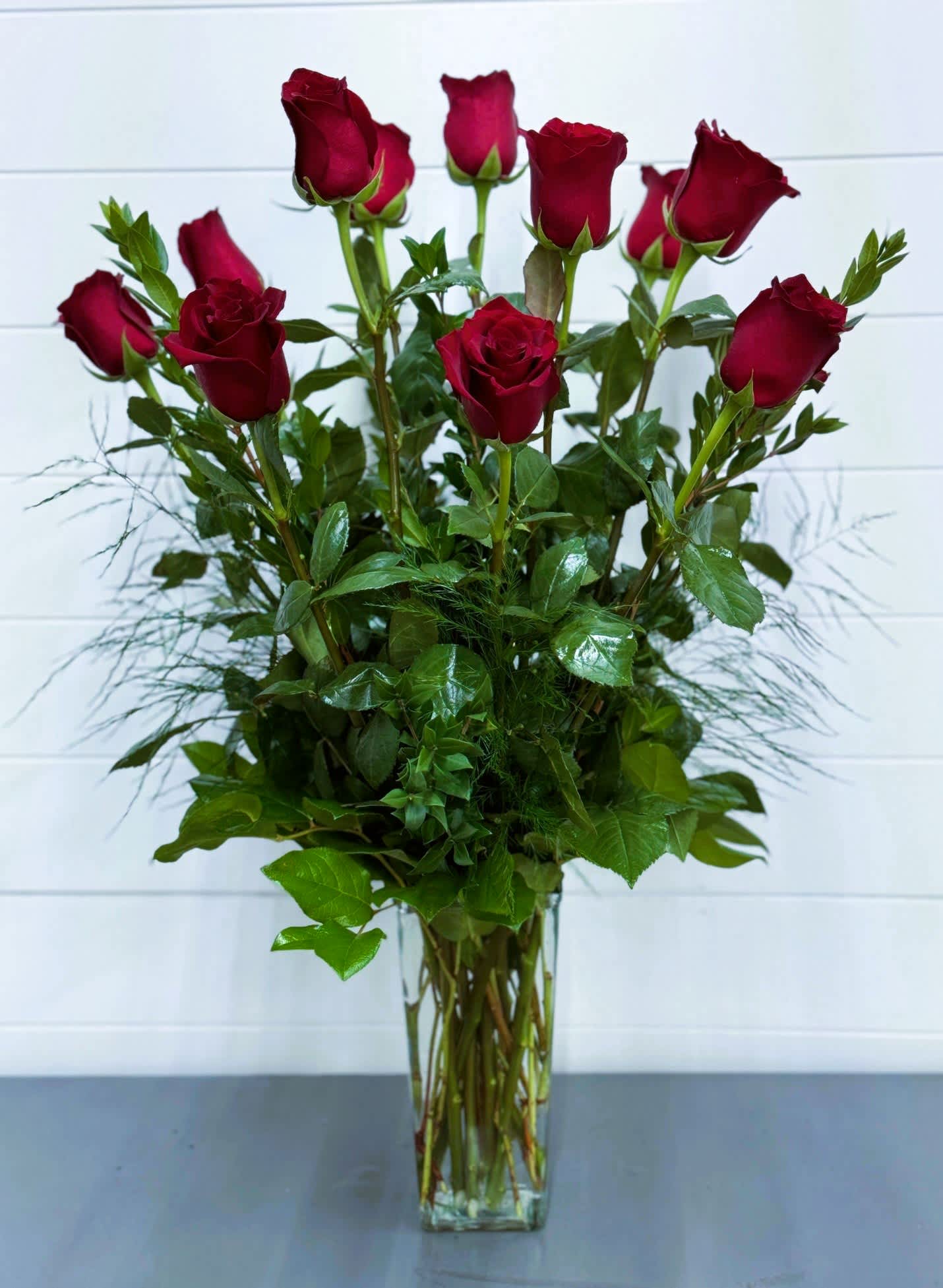 Tall bouquet of red roses in a clear glass vase