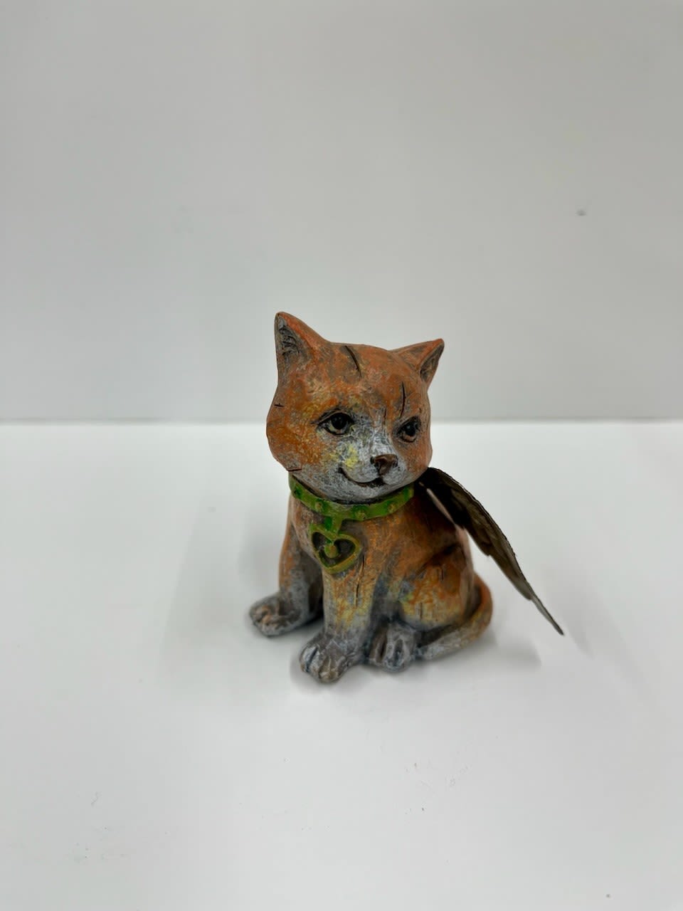 Small painted cat figurine with a green collar and feather wing