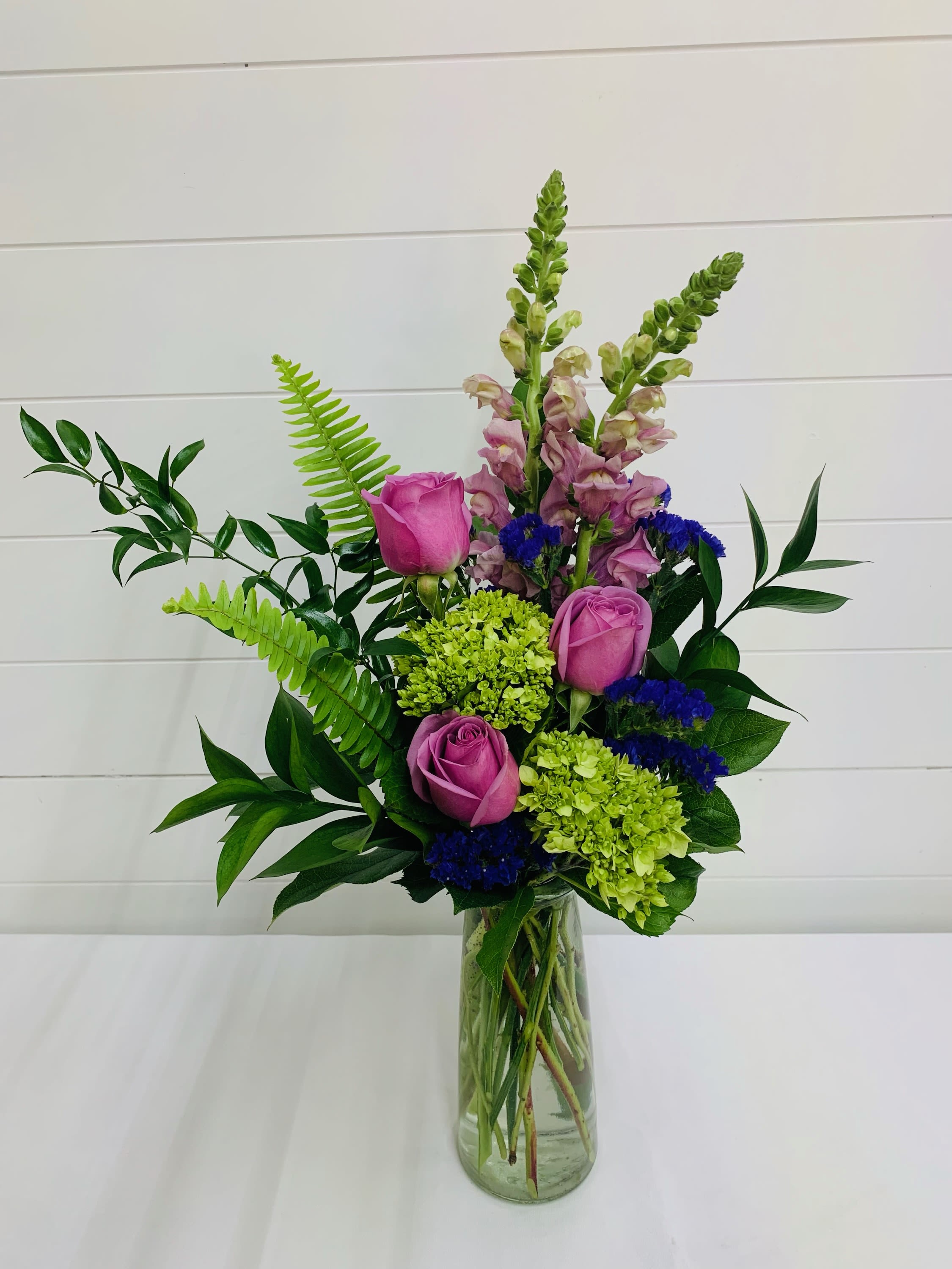 Pink roses and green hydrangeas in a clear glass vase