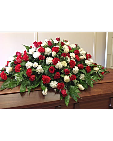 Red and white rose casket spray on a wooden casket