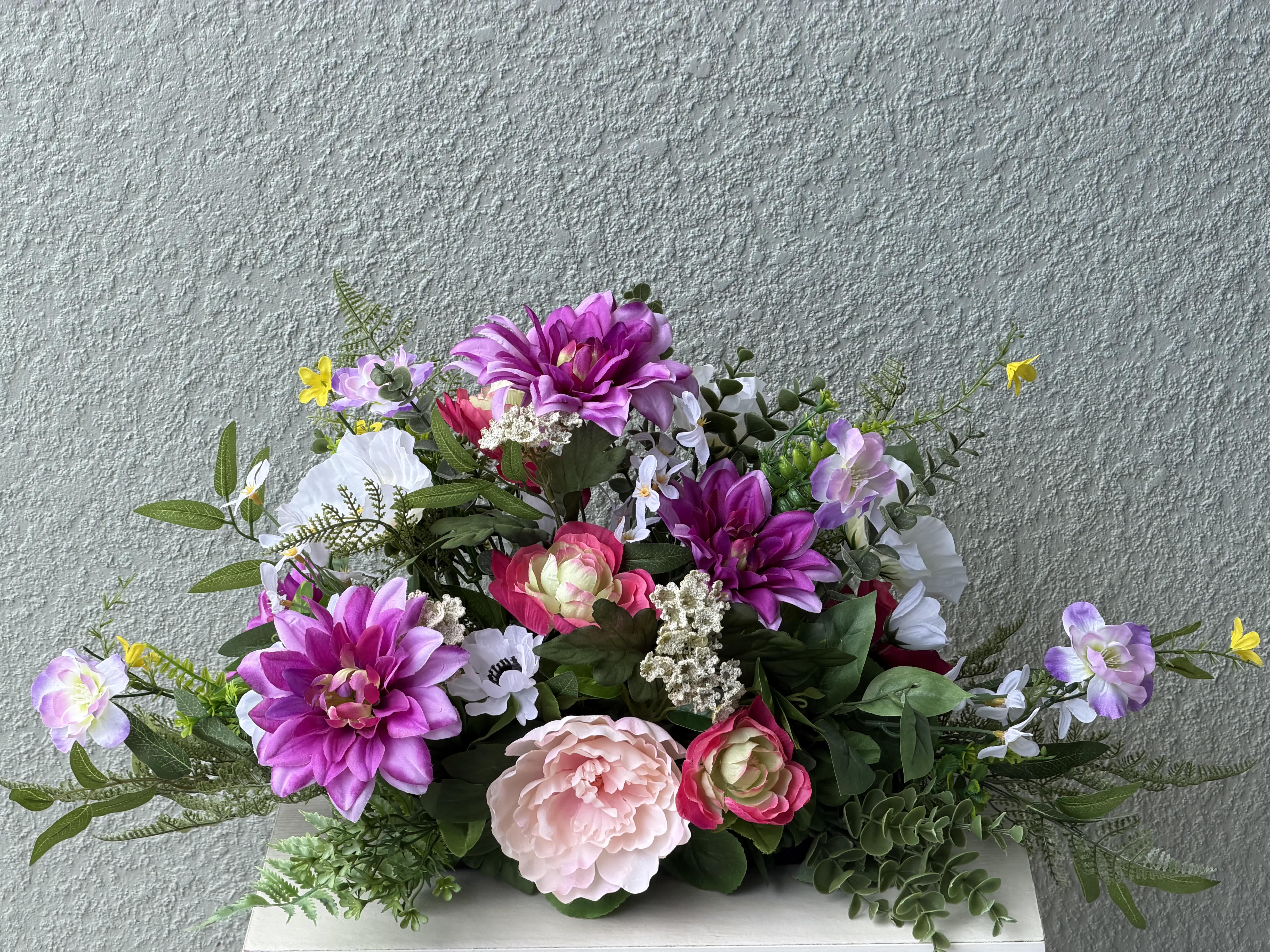 Mixed bouquet of pink, purple, and white flowers in a low arrangement