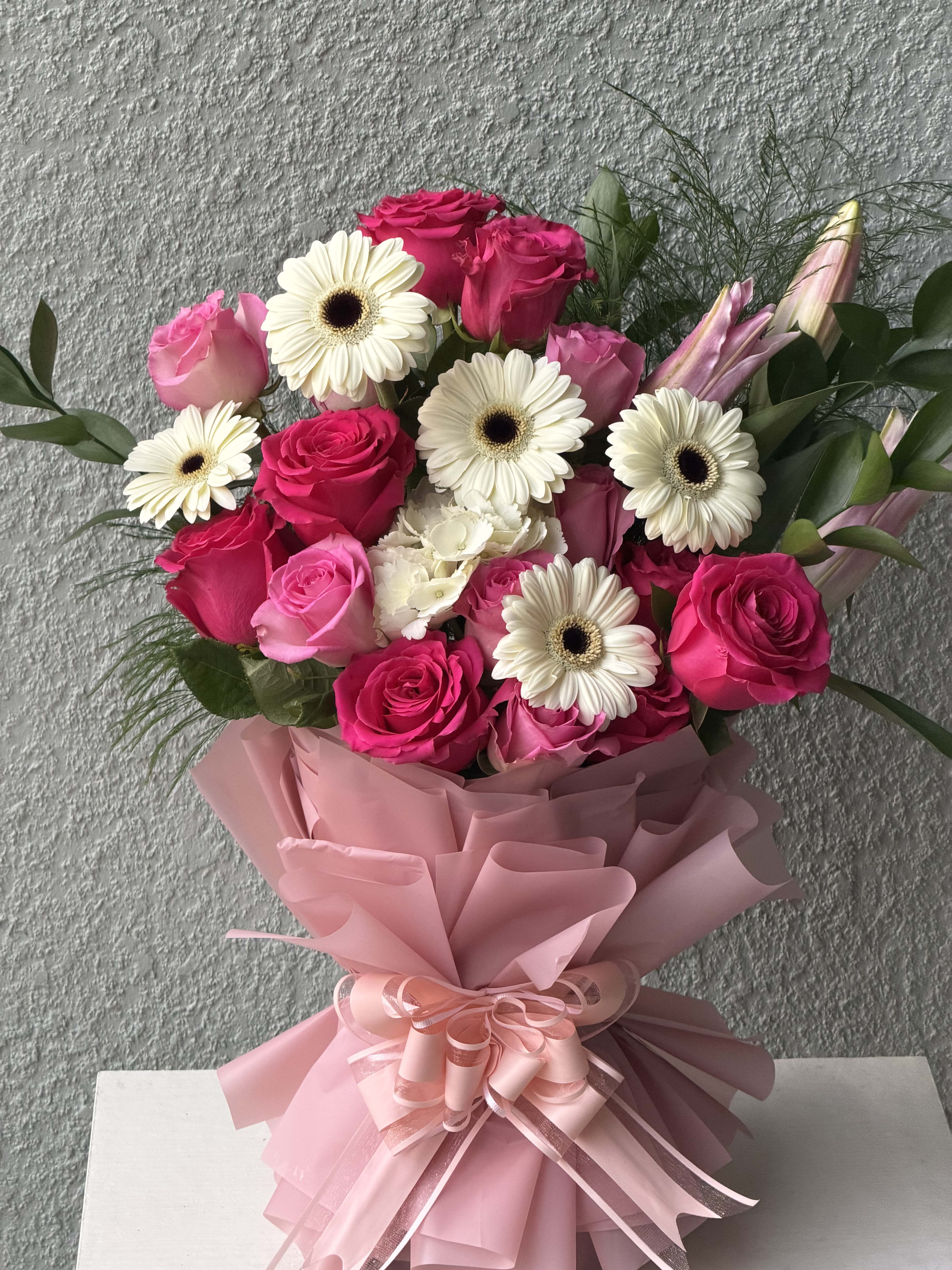 Bouquet of pink roses and white gerbera daisies wrapped in pink paper