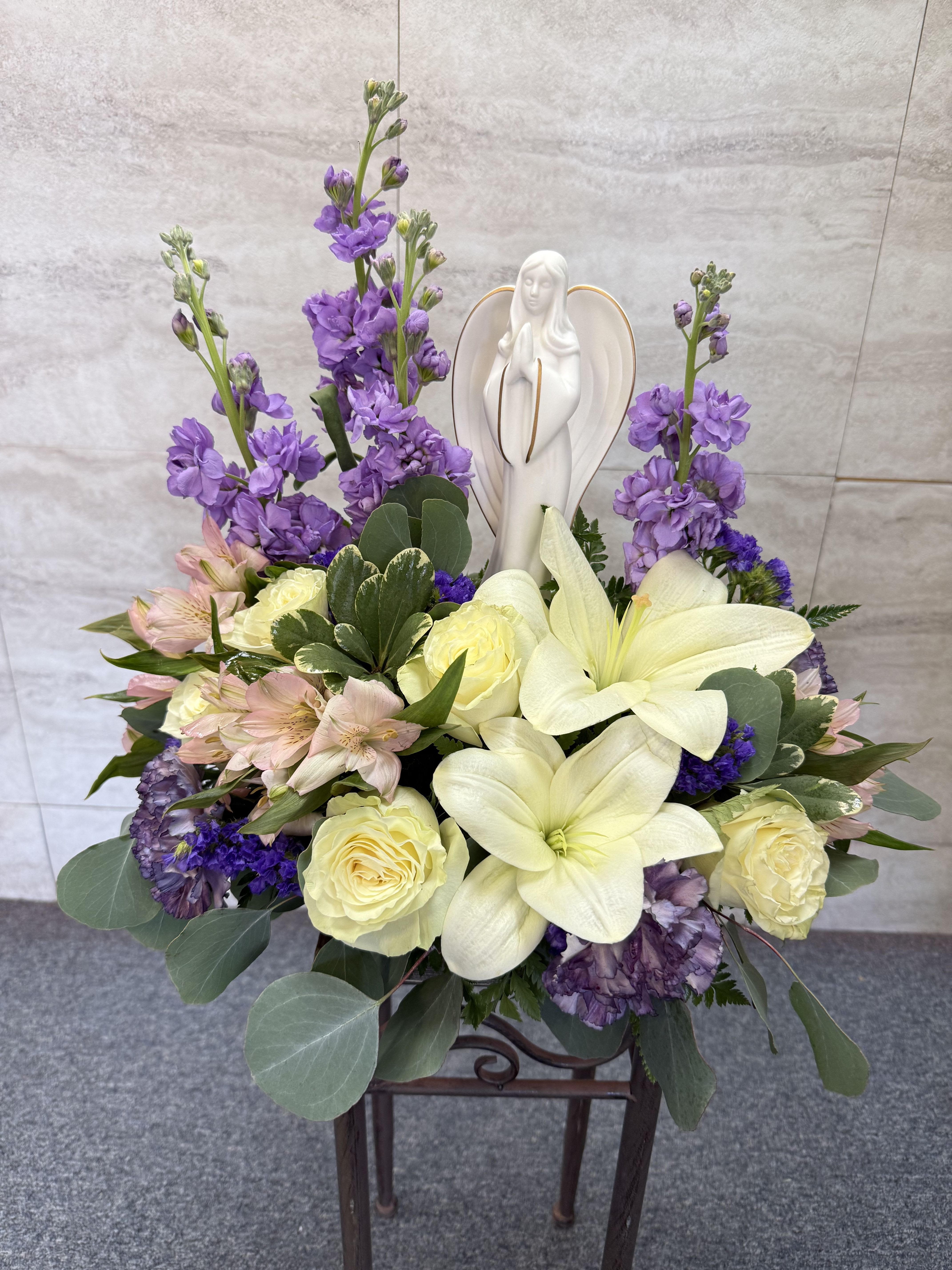 Purple and cream floral arrangement with a white angel figurine