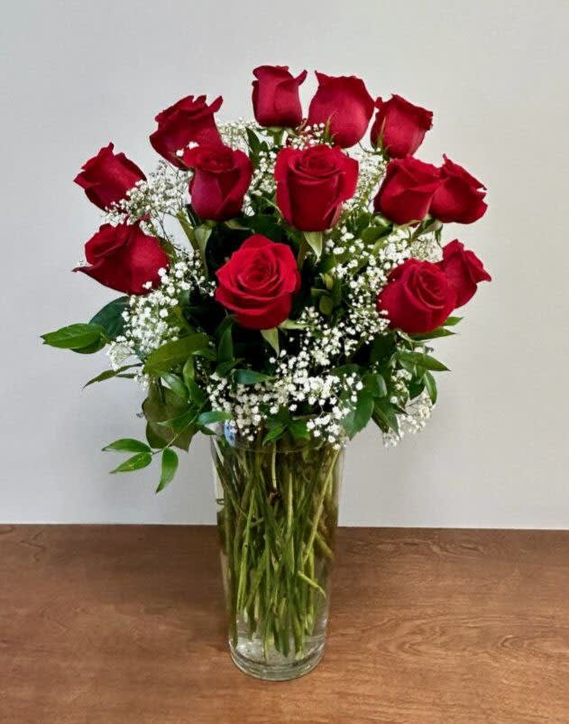 Red roses arranged in a clear glass vase with baby's breath