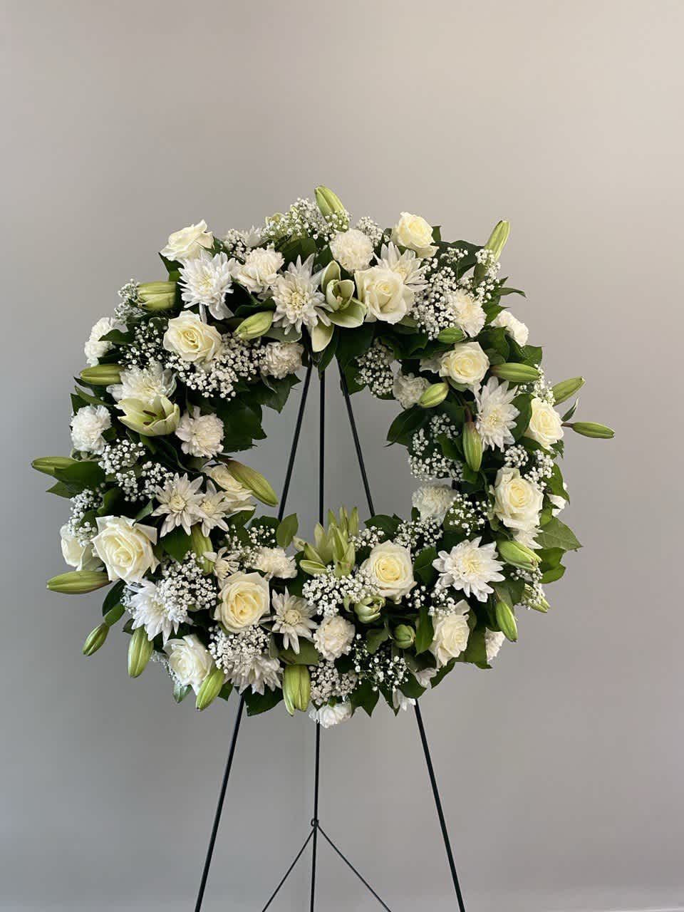 White floral wreath on a black stand