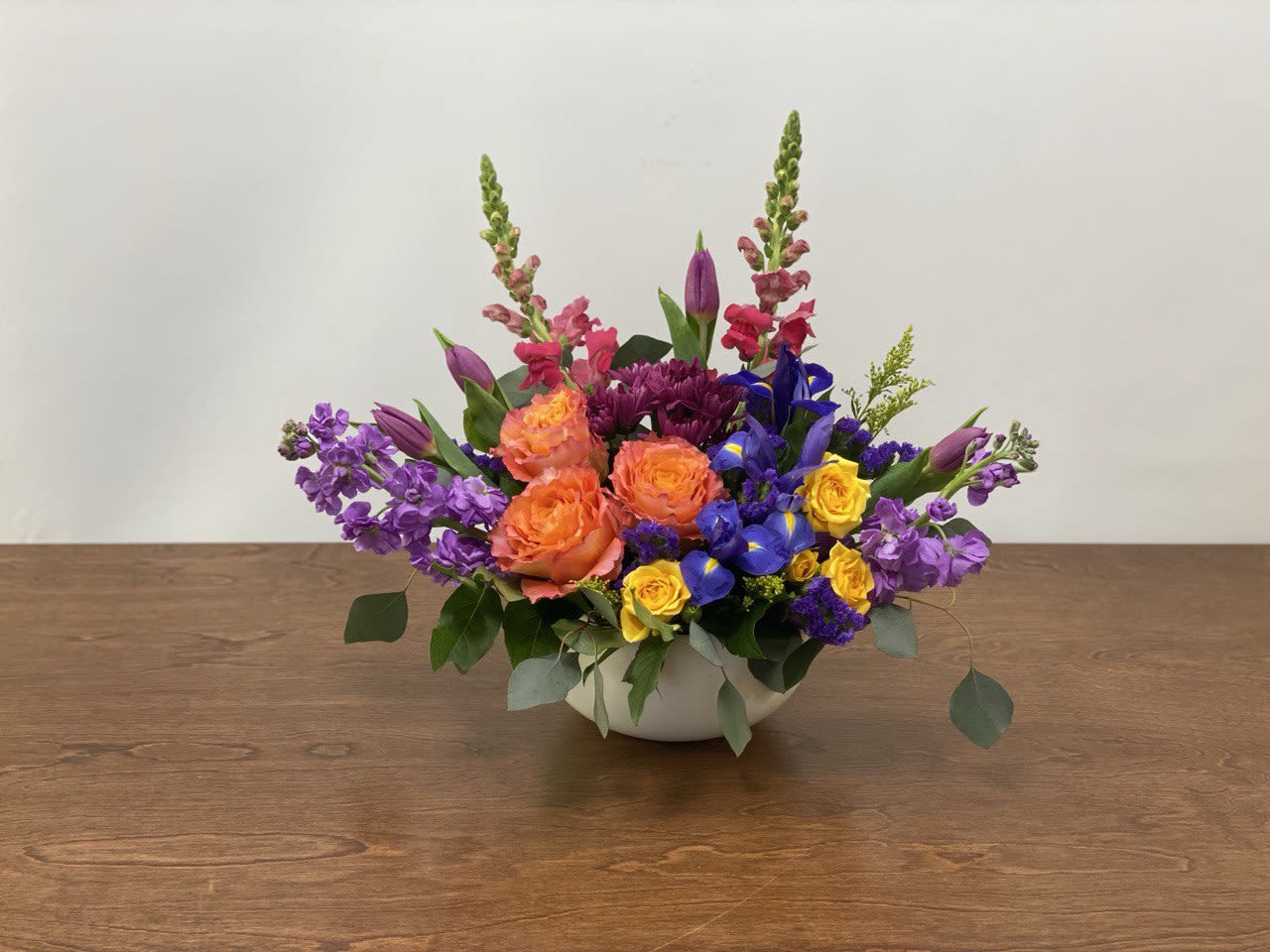 Colorful mixed flower arrangement in a white bowl vase