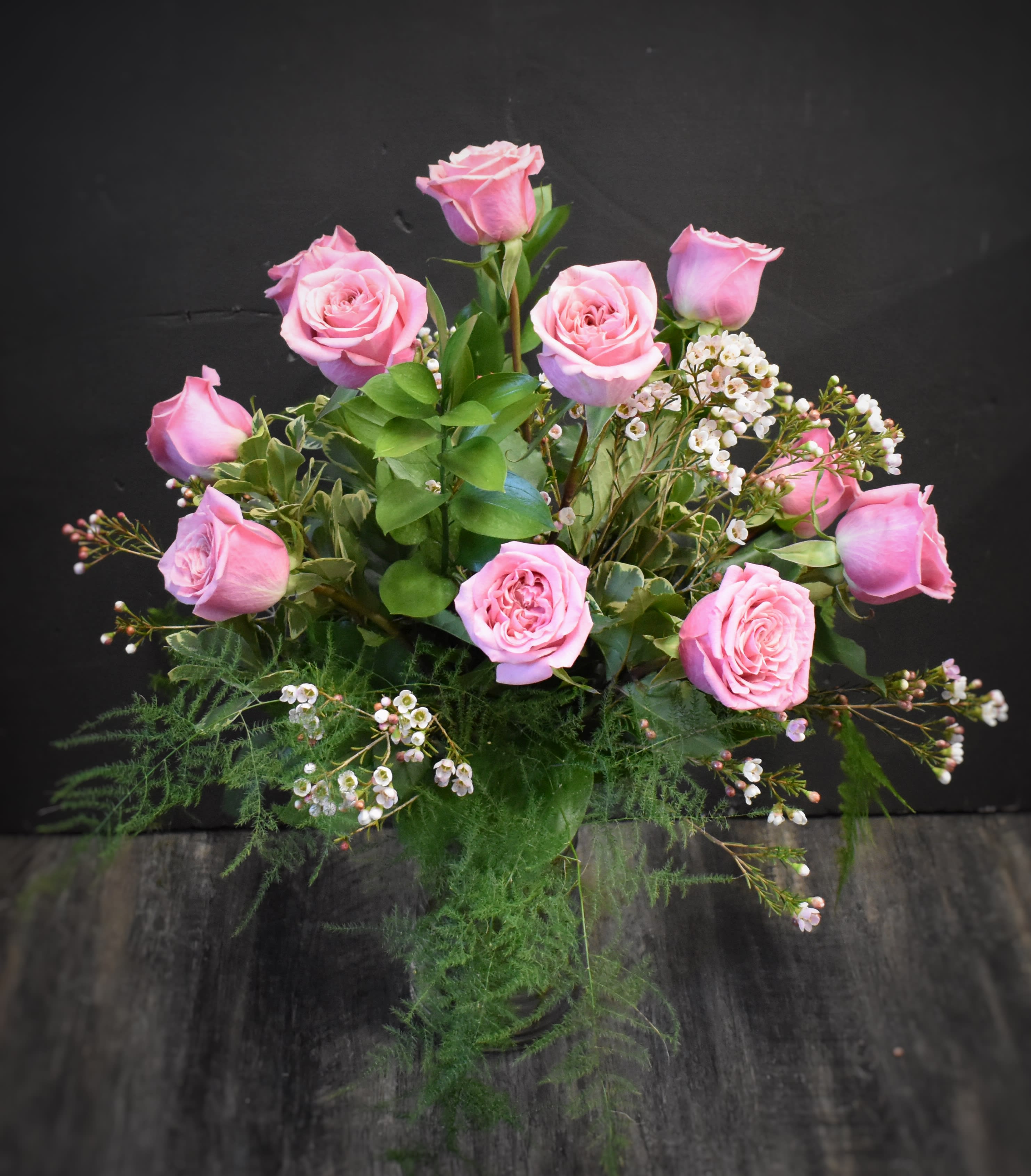 Arrangement of pink roses with small white blossoms in a clear glass vase