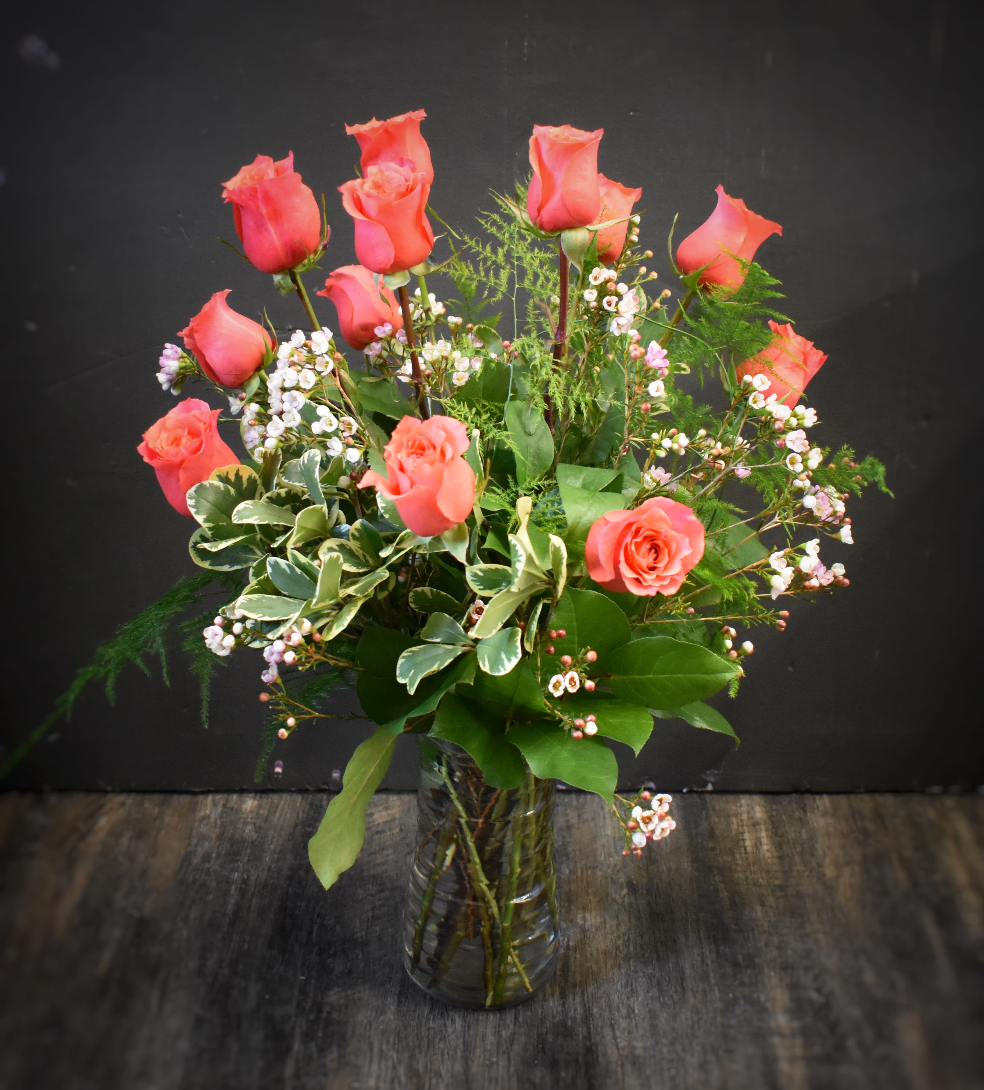 Pink roses arranged in a clear glass vase with small white filler flowers