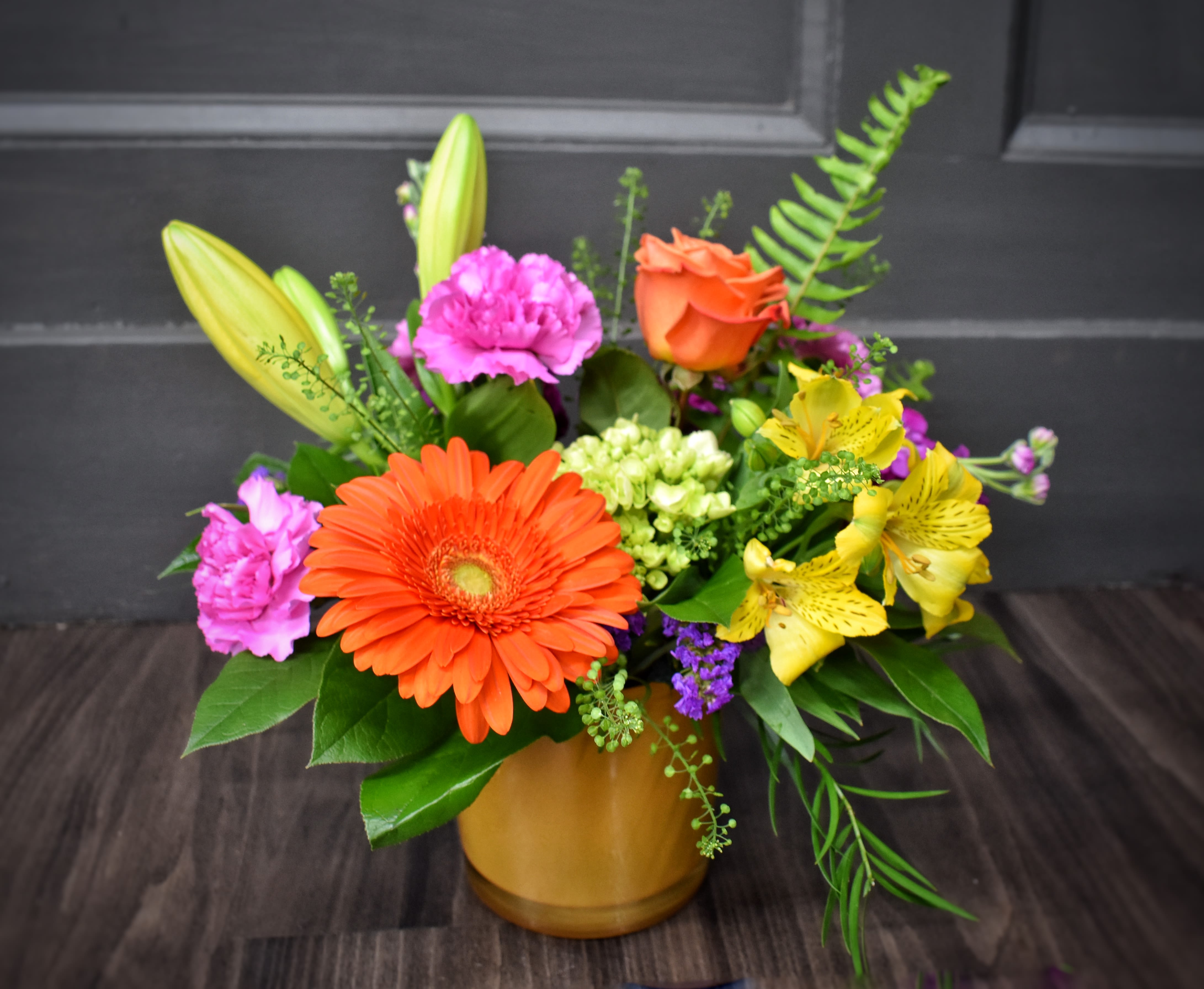 Calypso  - A bright, garden-style bouquet that reads like sunshine in bloom-Calypso is a mixed-color flower arrangement perfect as a birthday bouquet, congratulations gift, or a cheerful "just because" surprise. The lively mix of orange gerbera daisies and roses with pink carnations immediately feels celebratory, while yellow alstroemeria and lily buds add a fresh, uplifting energy that will make the person you're thinking of feel genuinely seen and loved.