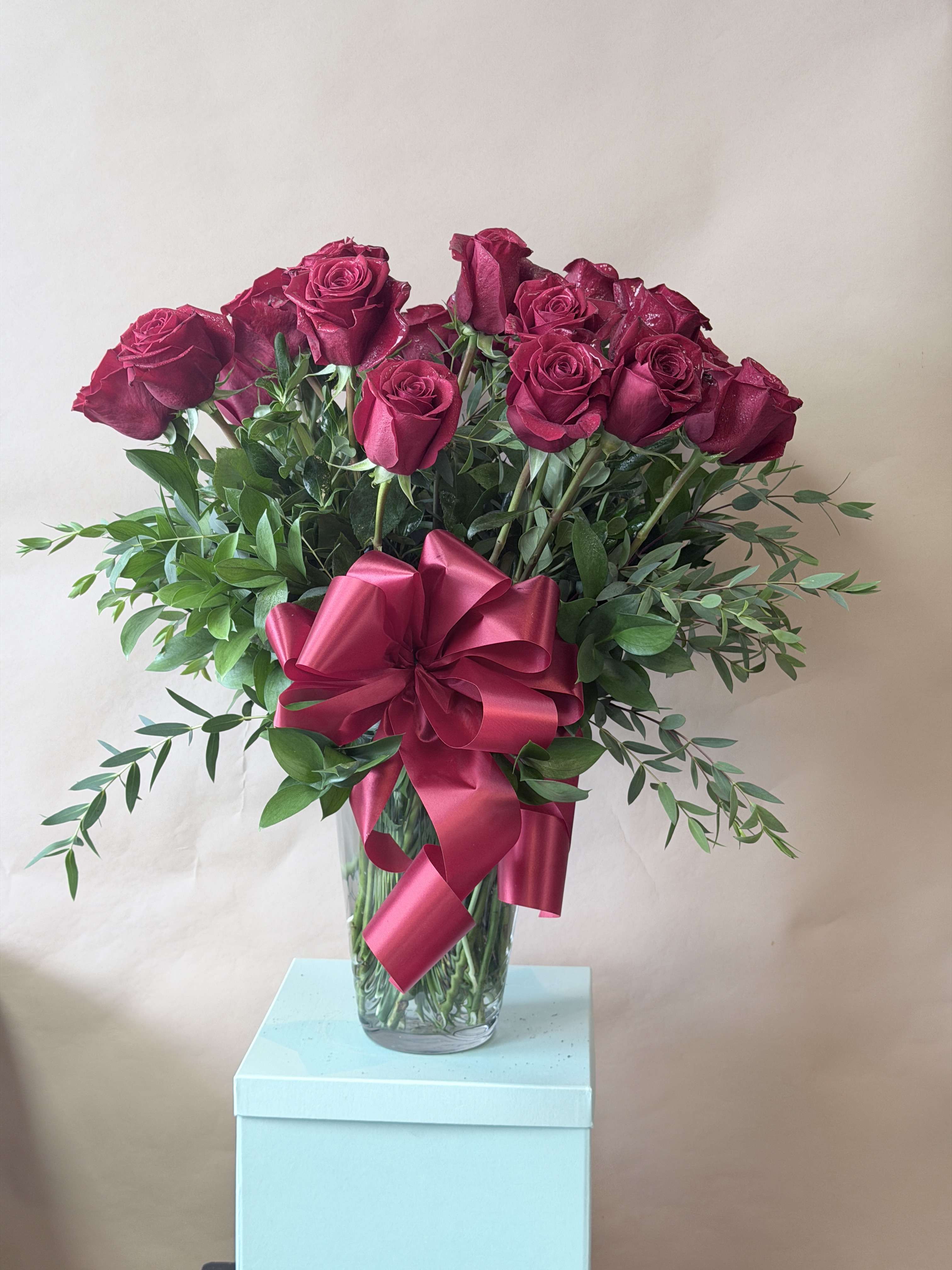 Bouquet of deep pink roses in a glass vase with a large ribbon