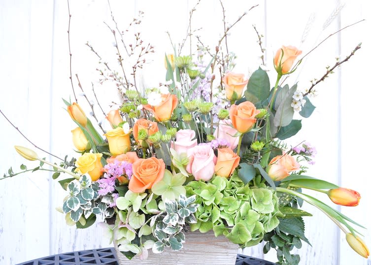Mixed bouquet of roses, tulips, and hydrangeas in a rectangular container