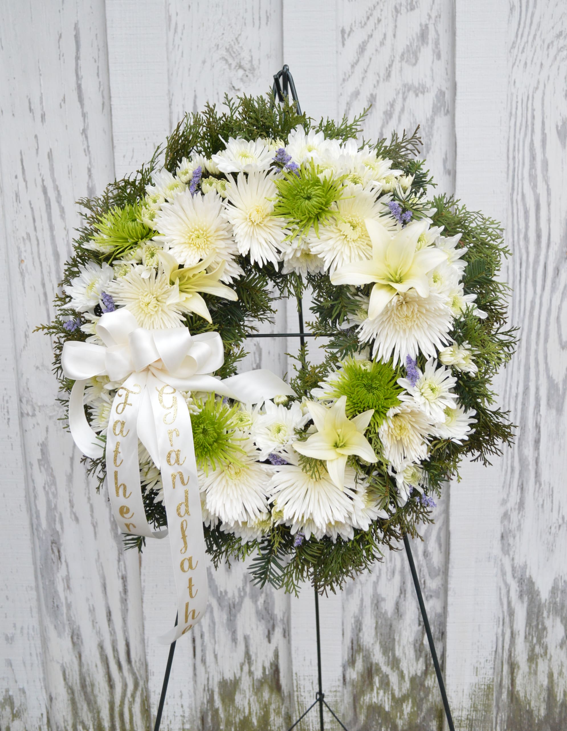 White floral wreath with a ribbon on a stand