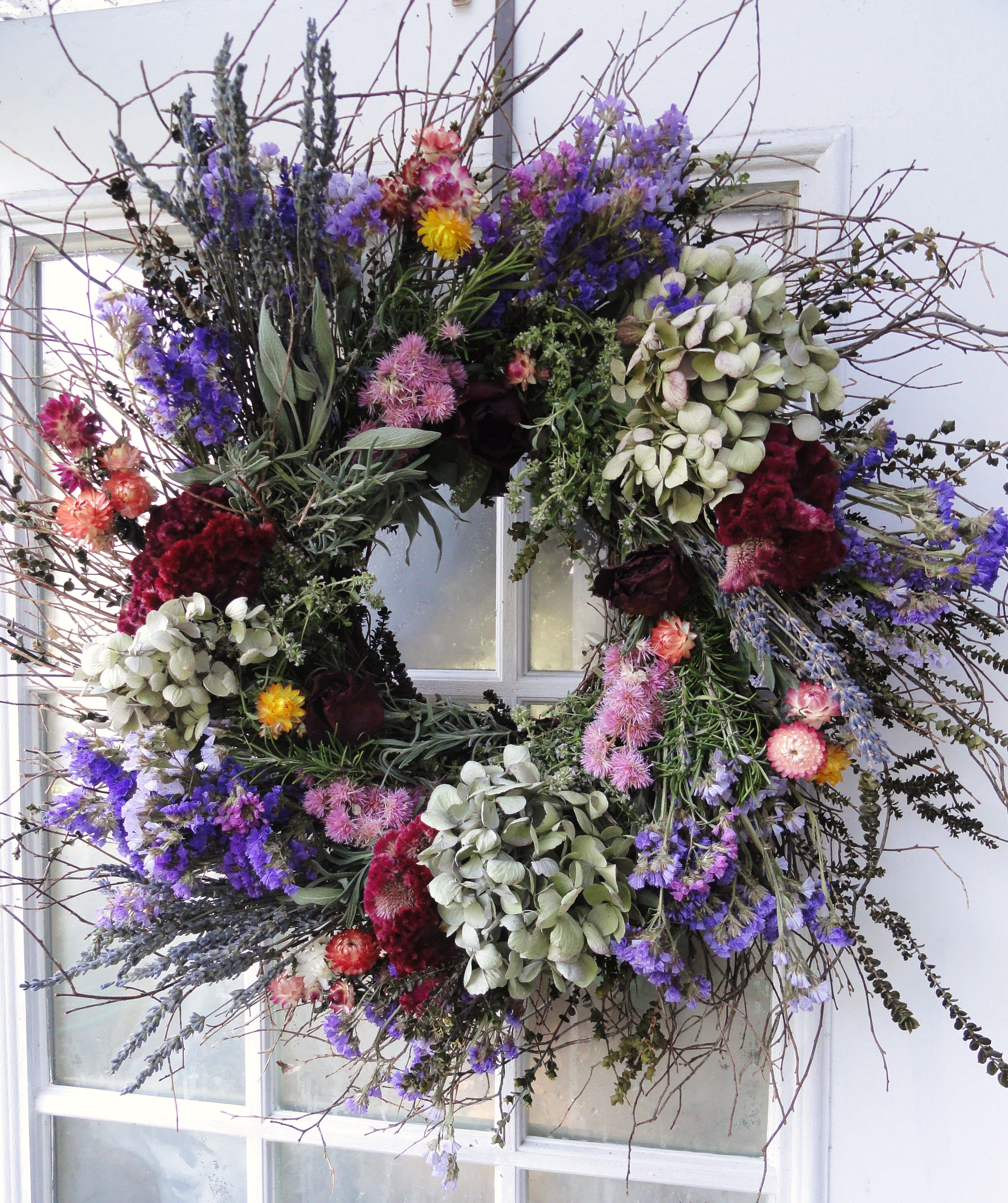 Large floral wreath with purple, pink, and white blooms on a window