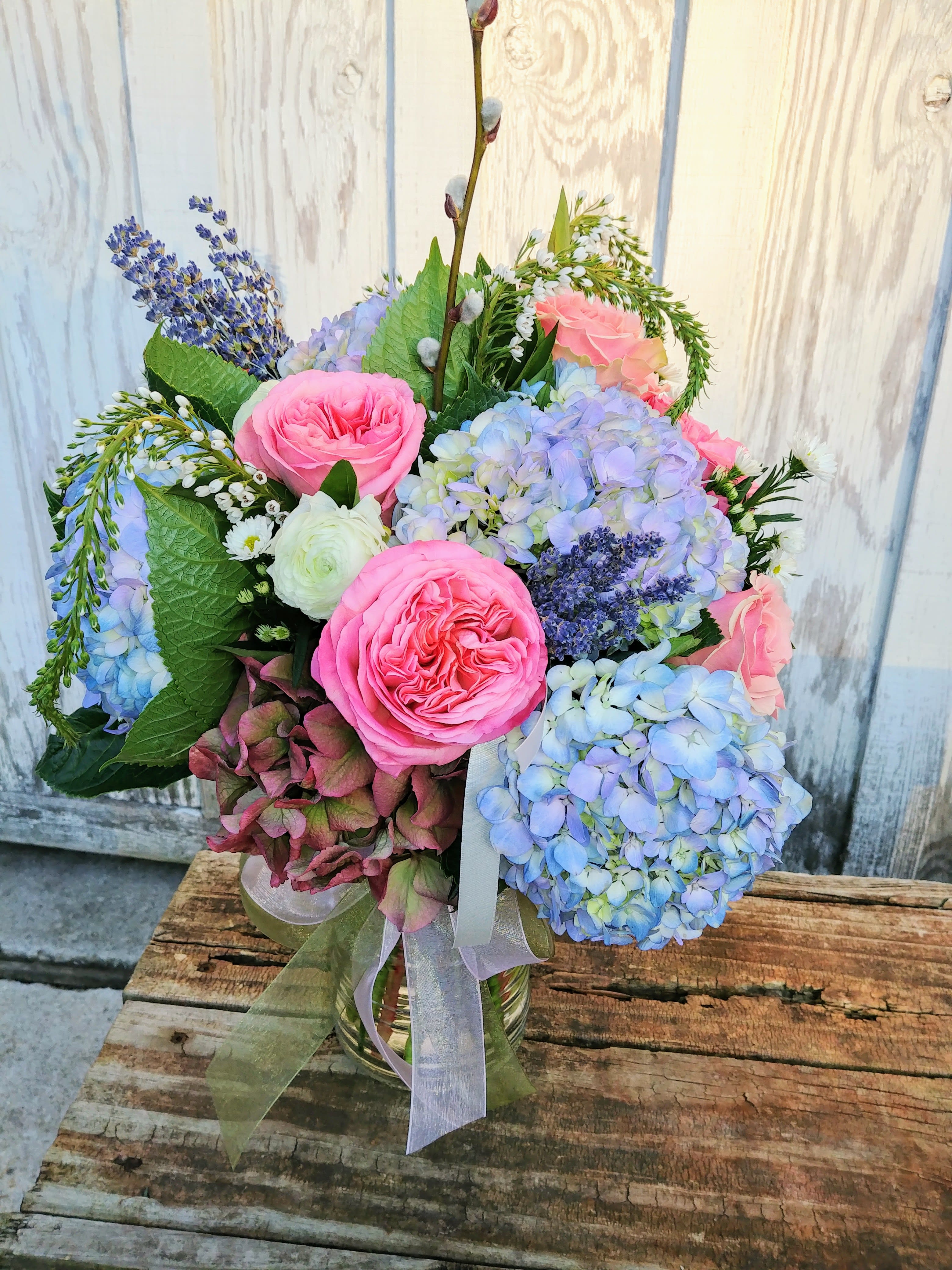Bouquet of pink roses and blue hydrangeas in a glass vase