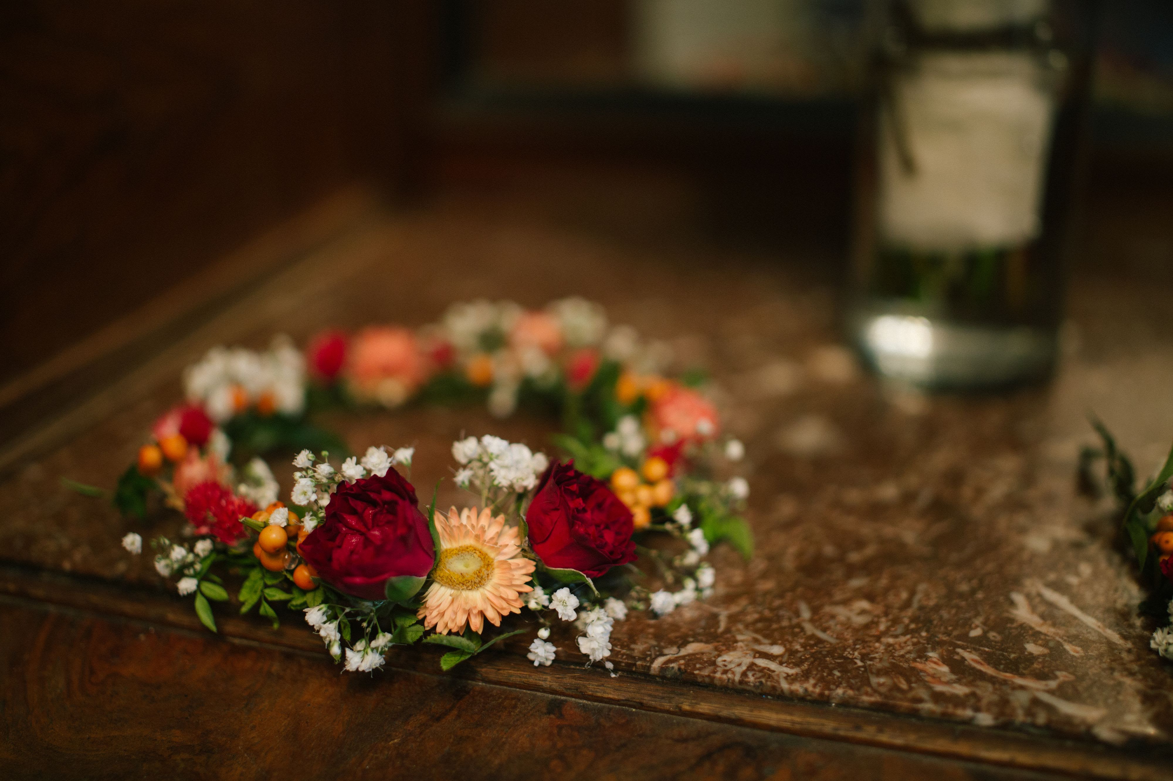 Floral crown with red roses and peach daisies on a table
