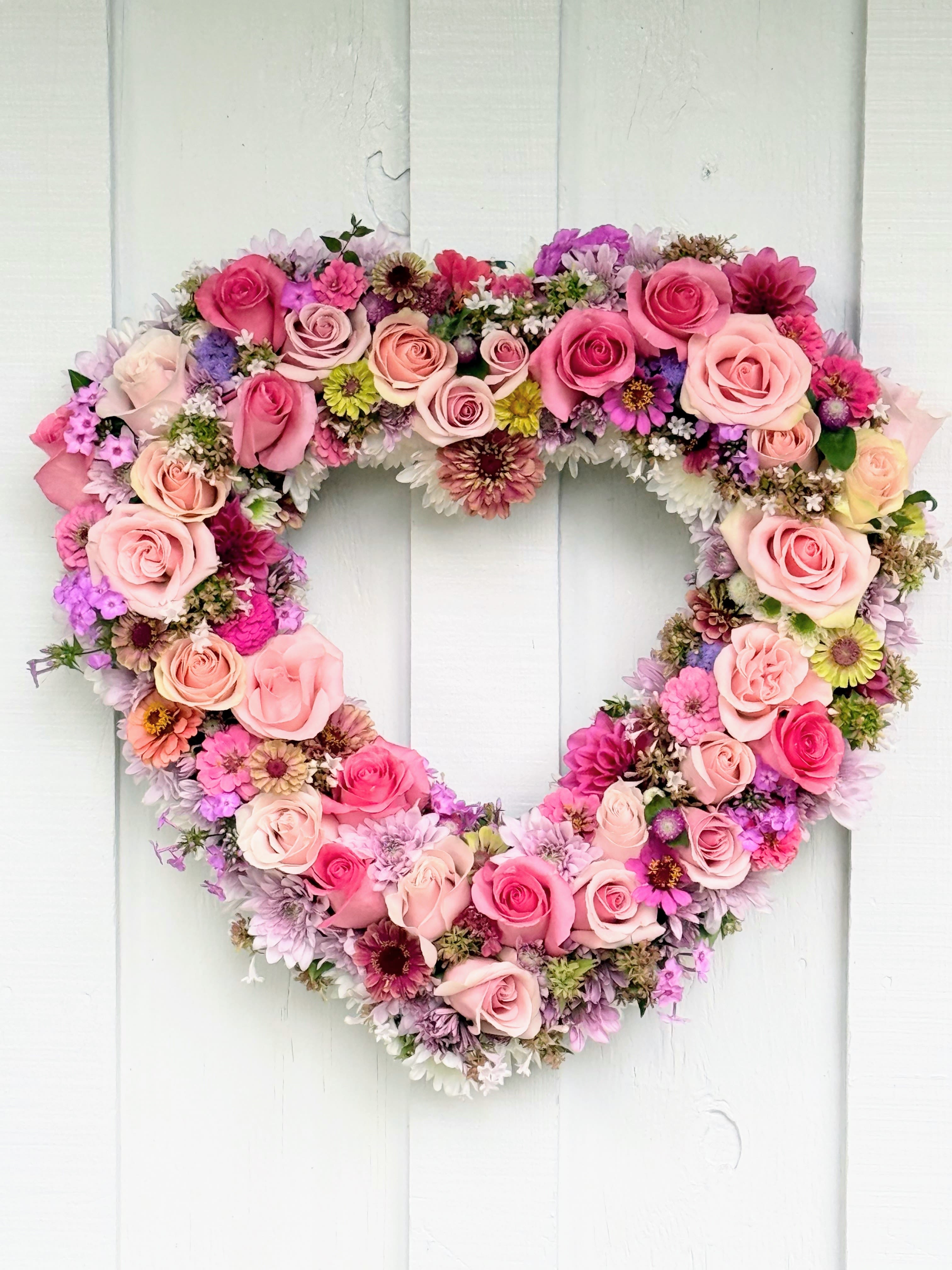 Heart-shaped floral wreath with pink roses and mixed blooms