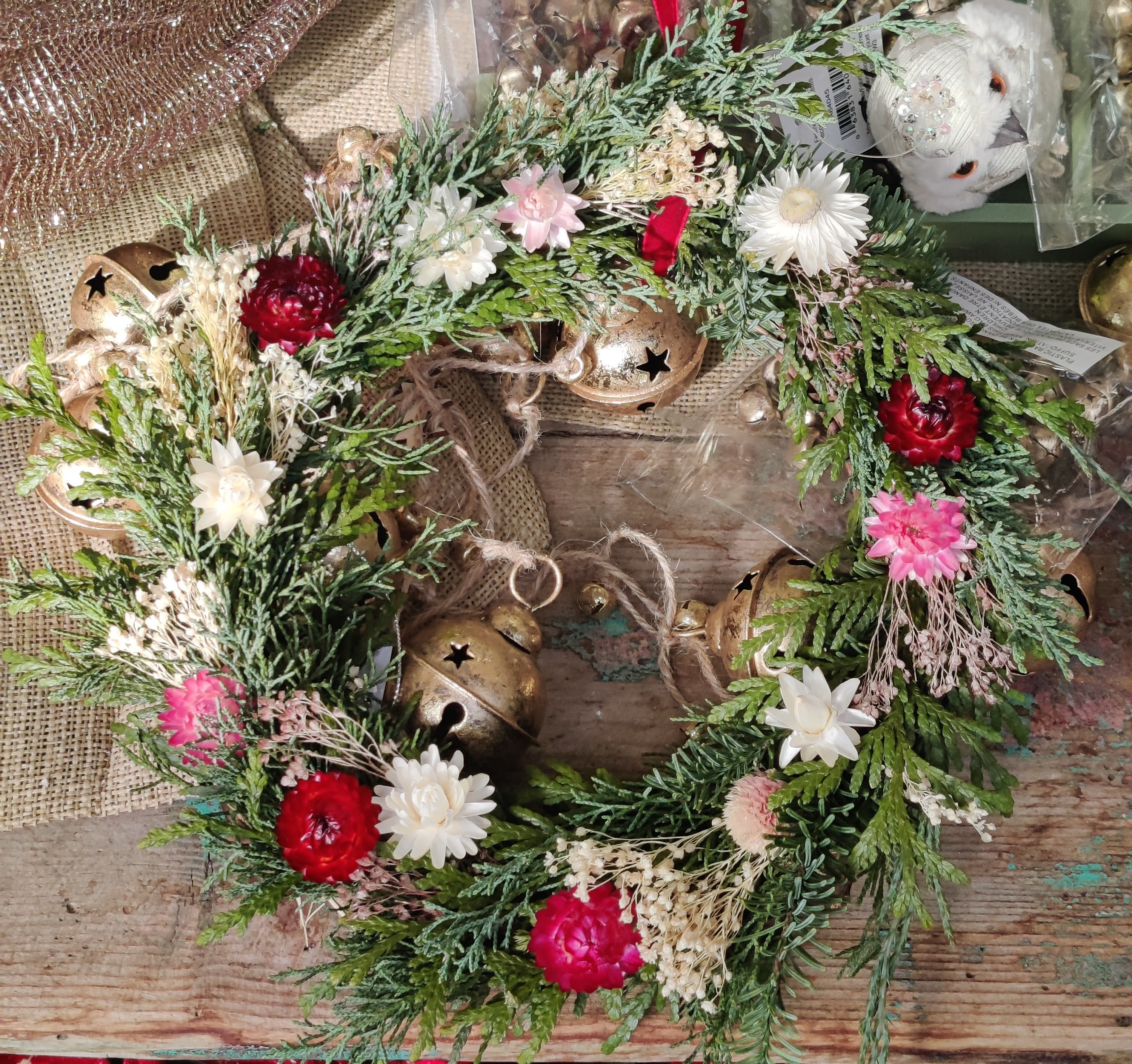 Floral wreath with red, pink, and white blooms and gold bells