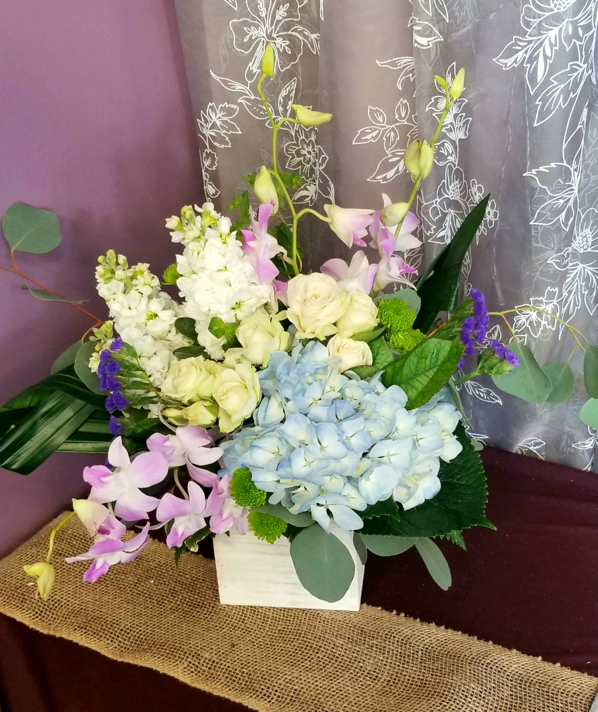 Mixed bouquet with blue hydrangea, white roses, and pink orchids in a white box