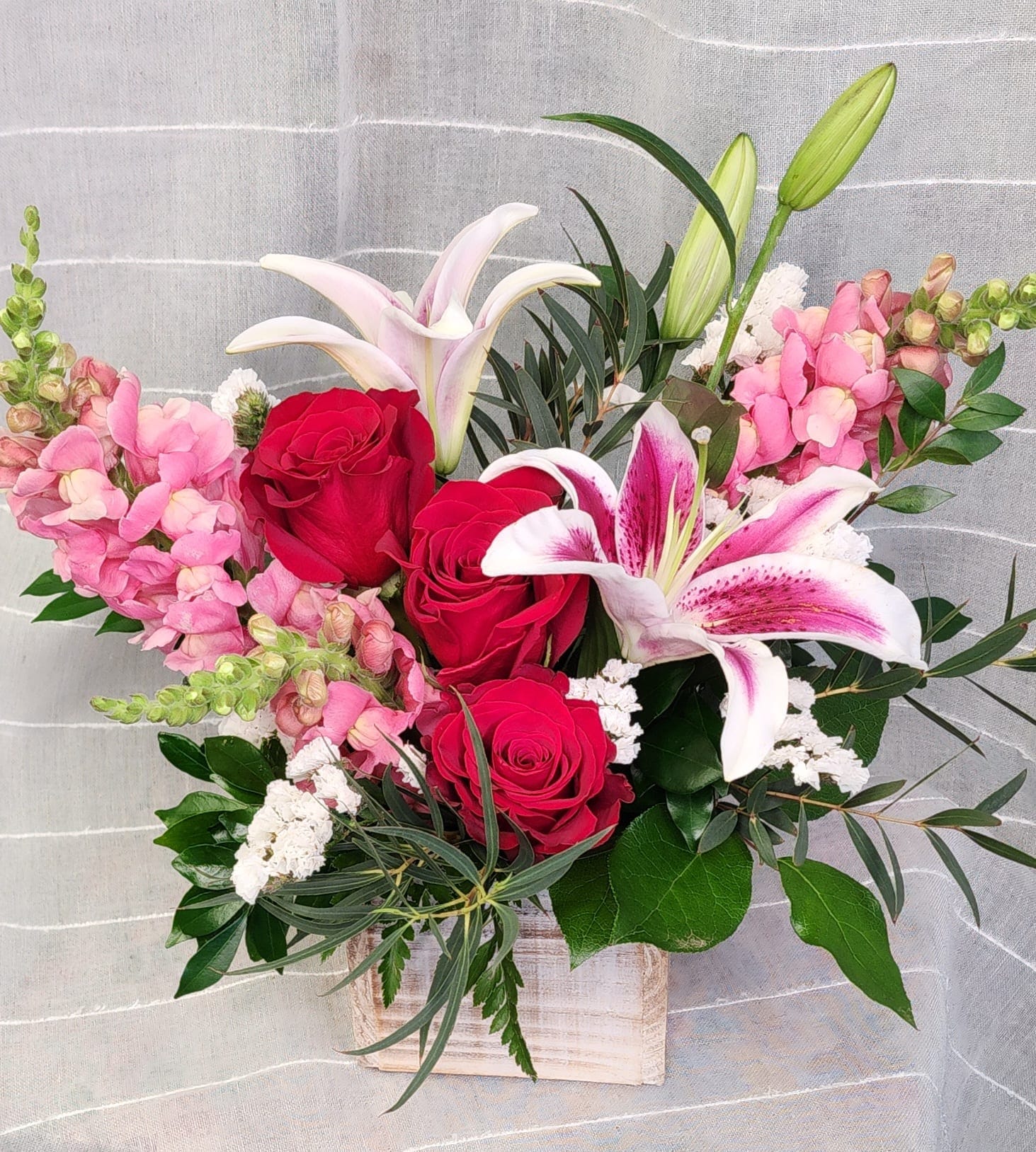 Bouquet of red roses and pink lilies in a wooden box